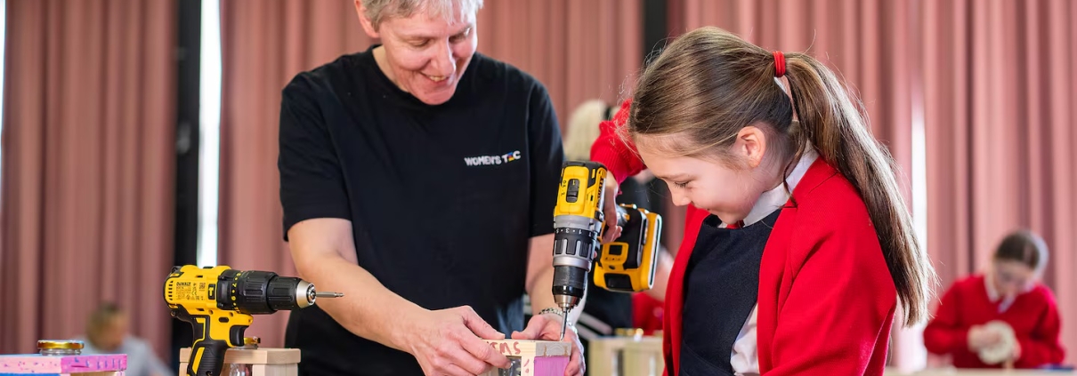 An adult woman and a girl looking at power tools.